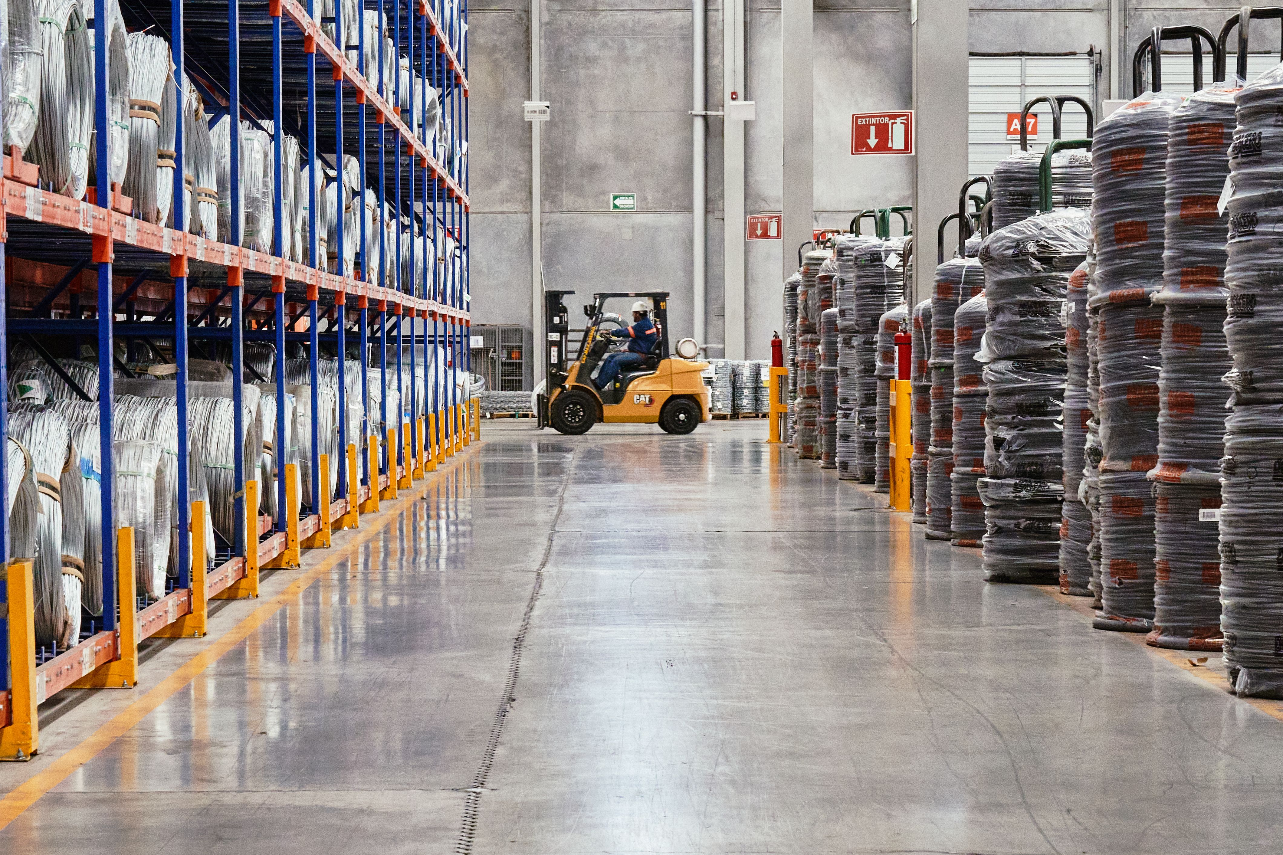 Warehouse aisle with high pallet racking and a forklift moving stock